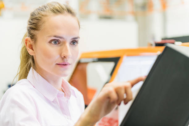 Horizontal color image of beautiful woman - manager working at warehouse and programming Cnc machine.