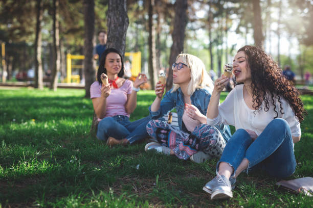istock Smiling teens eating ice cream at the park 950333526