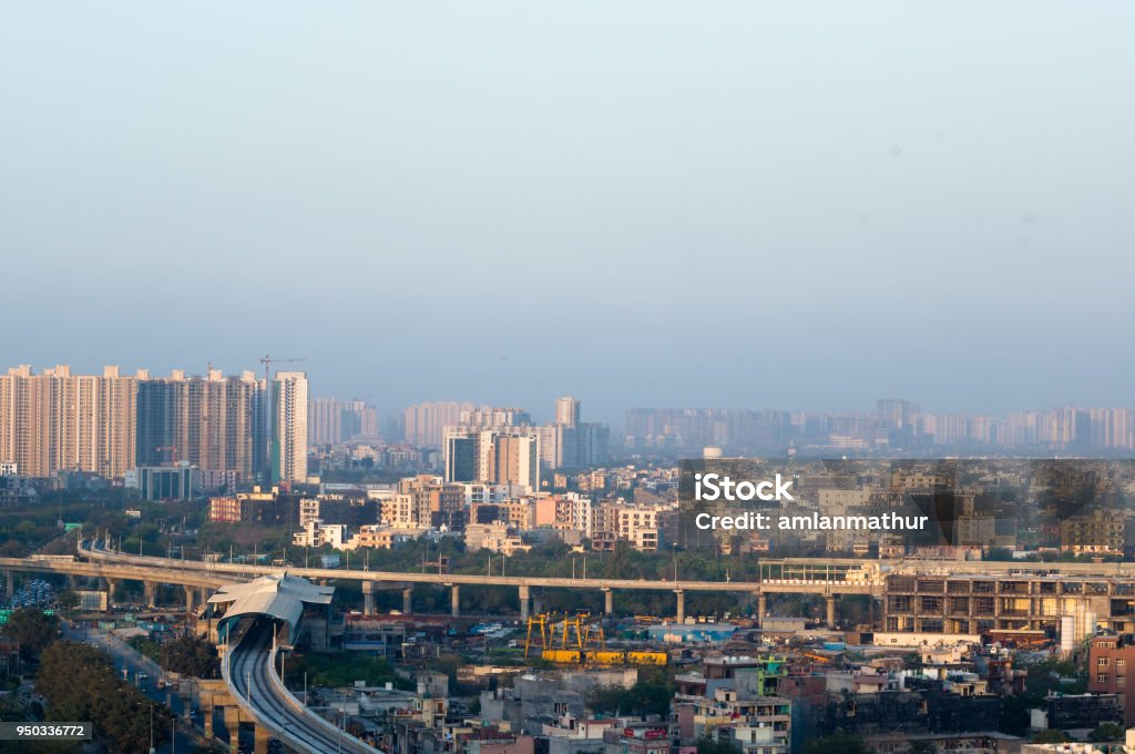 Noida Delhi cityscape with buildings and metro station Noida Delhi cityscape with skyscrapers, small houses and metro in the distance. Shows the amazing infrastructure in the city and transport options available India Stock Photo