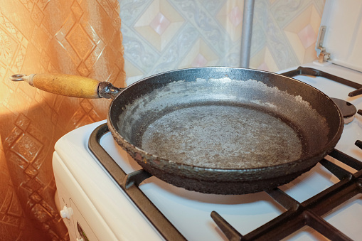 Old cast-iron frying pan on the gas stove in the kitchen