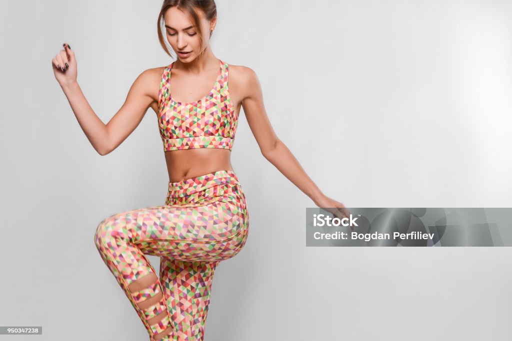 joyful active young woman jumping Slim young woman in sport outfit, tight colorful leggings and top with geometrical patterns in a motion, happy, joyful, jumping, isolated in studio One Woman Only Stock Photo