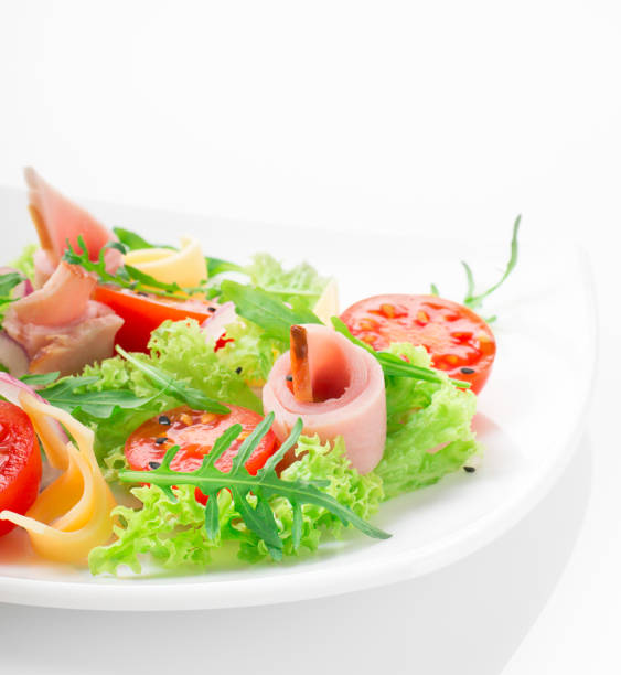 istock Fresh salad with tomatoes, arugula, cheese and ham on the white plate and white background 950355140