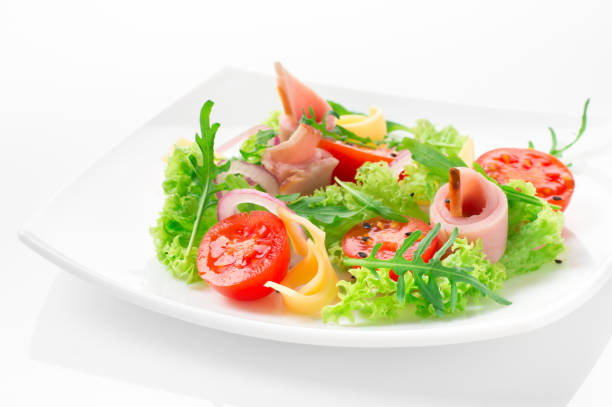 istock Fresh salad with tomatoes, arugula, cheese and ham on the white plate and white background 950355242