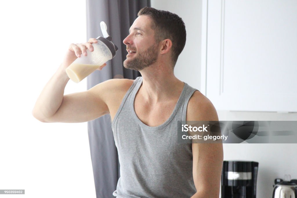 Protein Shake A man in a kitchen drinking a protein shake Protein Drink Stock Photo