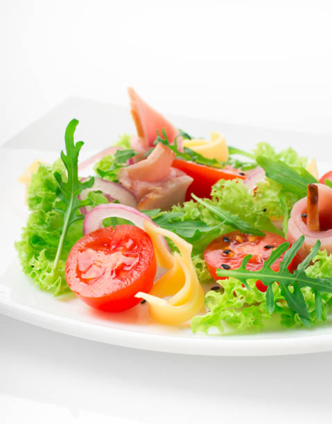 istock Fresh salad with tomatoes, arugula, cheese and ham on the white plate and white background 950355472