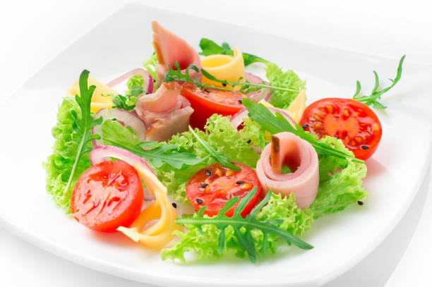 istock Fresh salad with tomatoes, arugula, cheese and ham on the white plate and white background 950355516