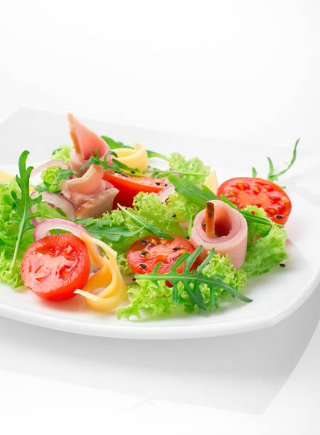 istock Fresh salad with tomatoes, arugula, cheese and ham on the white plate and white background 950355588