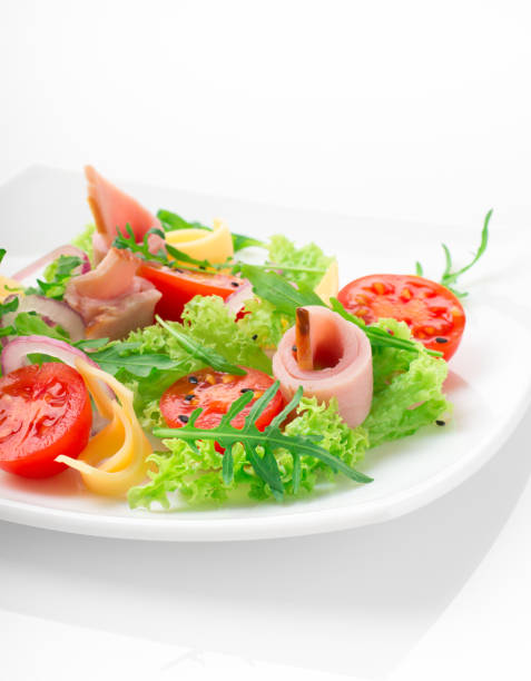 istock Fresh salad with tomatoes, arugula, cheese and ham on the white plate and white background 950355640