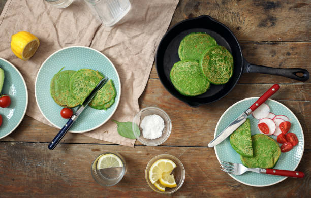 istock Healthy breakfast table concept. Spinach pancakes with vegetables and water with lemon on a wooden table, top view 950356788