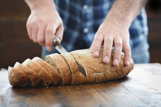 istock Male hands cut bread on a wooden table 950356868
