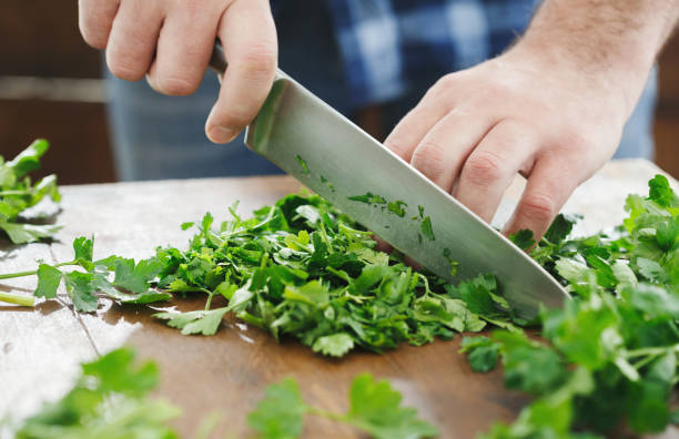 l'uomo sta cucinando il prezzemolo sul tavolo di legno da vicino - parsley cilantro herb freshness foto e immagini stock