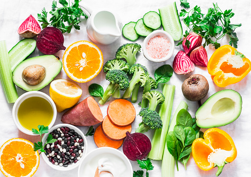 Five best vitamins for beautiful skin. Products with vitamins A, B, C, E, K - broccoli, sweet potatoes, orange, avocado, spinach, peppers, olive oil, dairy, beets, cucumber, beens. Flat lay, top view