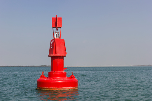 Floating red navigational buoy on blue sea