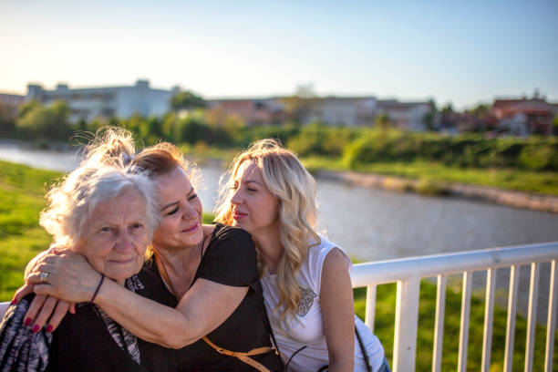 Beautiful young daughter is hugging her senior smiling mother - isolated on white background