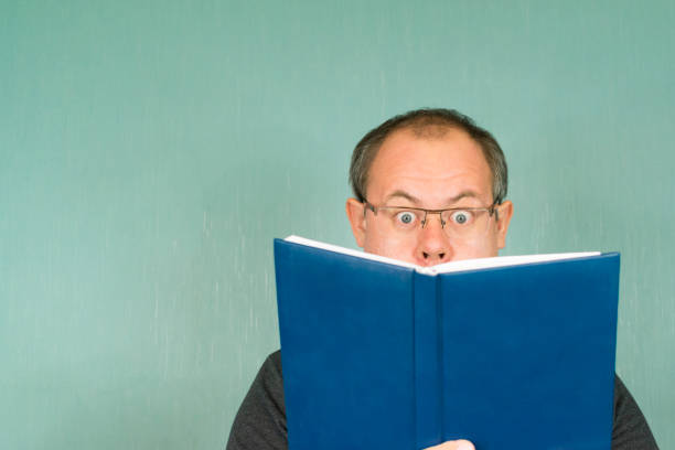 istock the man is enthusiastically reading a book in a blue cover on an empty background 950372840