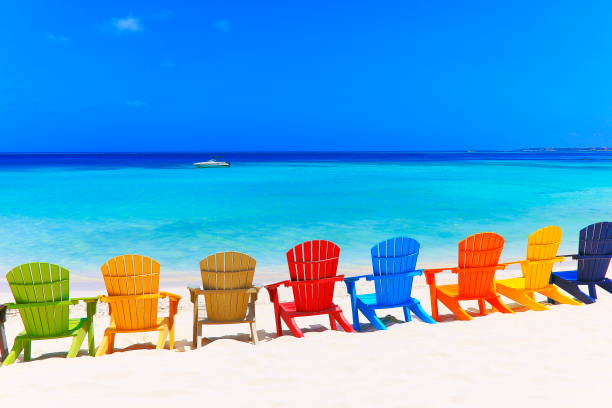 contemplazione: tropical beach con sedie colorate adirondack e motoscafo - mar dei caraibi - adirondack chair foto e immagini stock