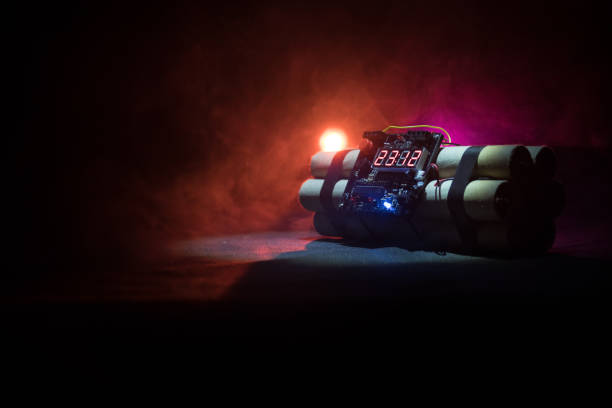istock Image of a time bomb against dark background. Timer counting down to detonation illuminated in a shaft light shining through the darkness 950409052