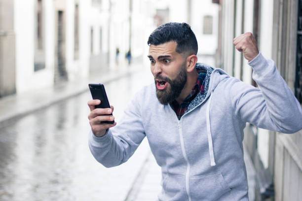 Enthusiastic young man looking at cellphone