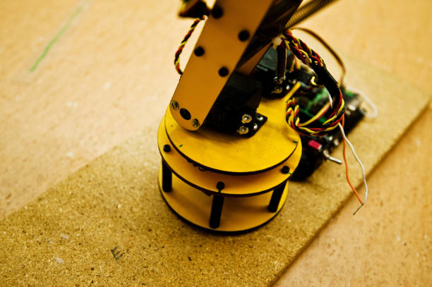 istock Yellow Robotic Arm On A Wooden Surface in The Laboratory 950419484
