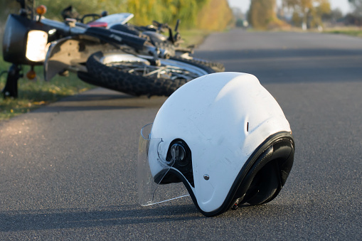 Photo of helmet and motorcycle on road, the concept of road accidents