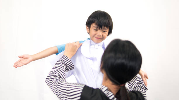 istock Cute child standing and mom checking size of new school uniform 950425178