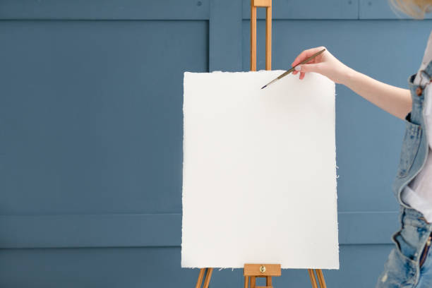 drawing lessons. art classes. painting school. learn to create pictures. woman starting to draw on blank canvas or watercolor paper on easel.