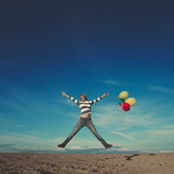 istock woman jumping with birthday balloons 950437544