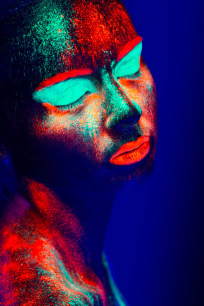 istock Women Portrait with Glowing Colored makeup in black light 950439444