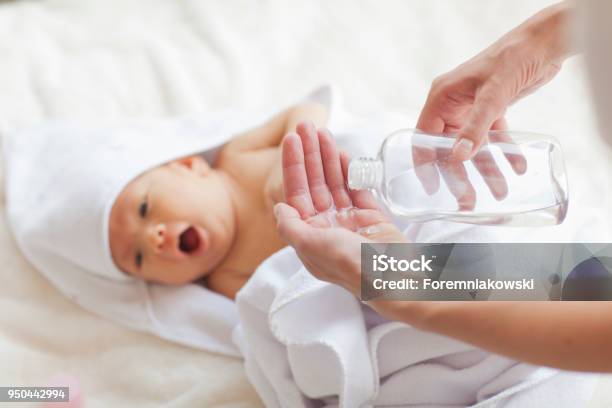 Young Mother Is Applying A Body Oil On The Newborn Stock Photo - Download Image Now