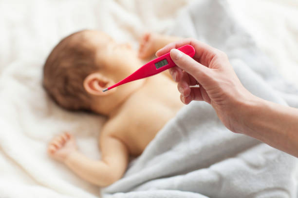 Little baby is sick. Mum measuring his temperature by electronic thermometer. fever stock pictures, royalty-free photos & images