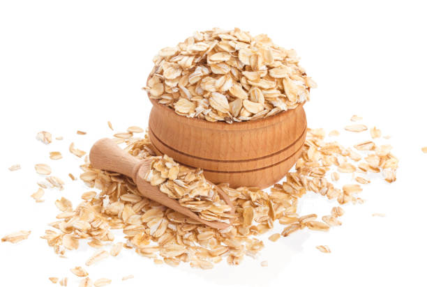 istock Oat flakes in wooden bowl isolated on white background 950452232