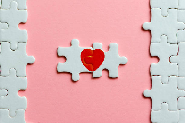 two pieces of a puzzle with red heart on pink background