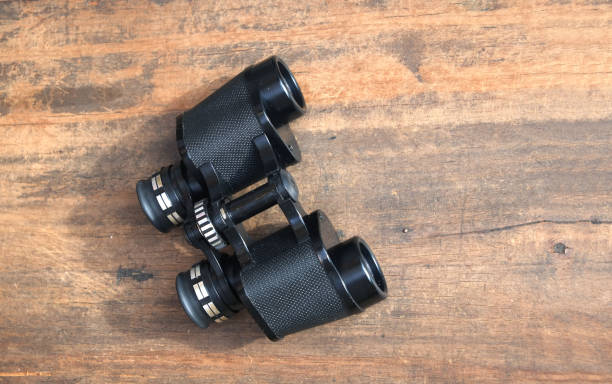 binoculares de prisma vintage negro color en fondo madera closeup - binoculars watching optical instrument closed fotografías e imágenes de stock