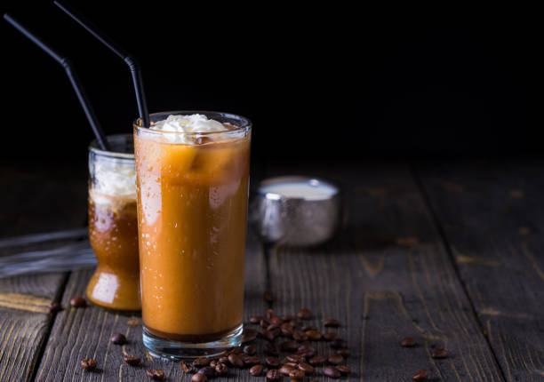 istock Ice coffee in a tall glass on dark natural desk. 950457264