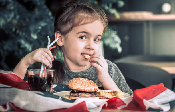 istock little girl in cafe with burger 950457312