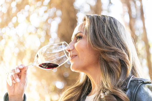 mature hispanic woman posing drinking a glass of wine at her winery
