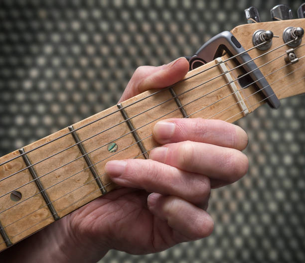istock Guitarist playing D chord with amplifier speaker background. 950469362