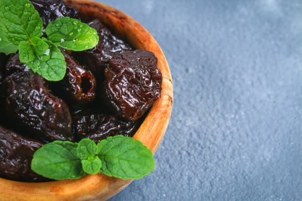 istock Prunes and fresh mint leaves in a bowl on a concrete table. 950472708