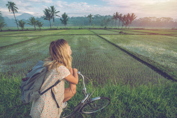 Young woman on bicycle stops to admire rice fields, Indonesia Cheerful young woman cycling in the country side of Indonesia, stops to look at the rice fields, Borobudur, Central Java, Indonesia. People travel recreational activities concept central java province stock pictures, royalty-free photos & images