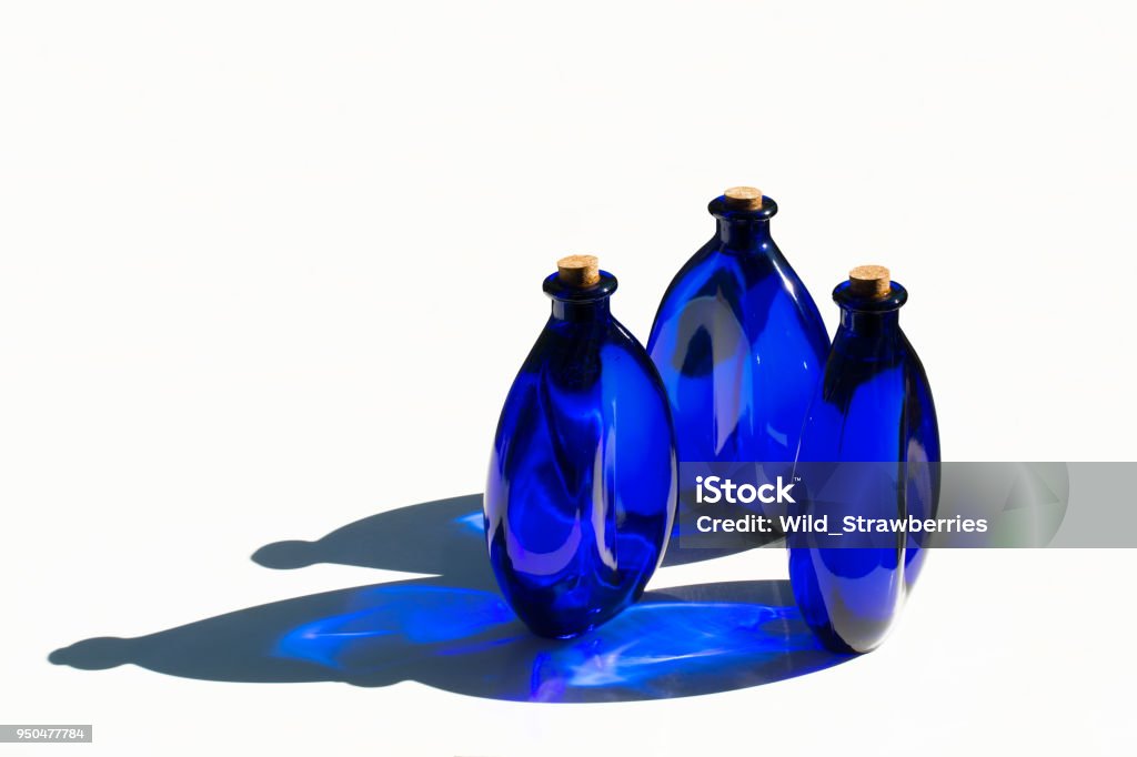 Blue solar water in blue glass bottles isolated on white. Blue solar water in blue glass bottles sealed with cork stoppers. Isolated on white background. Blue Stock Photo