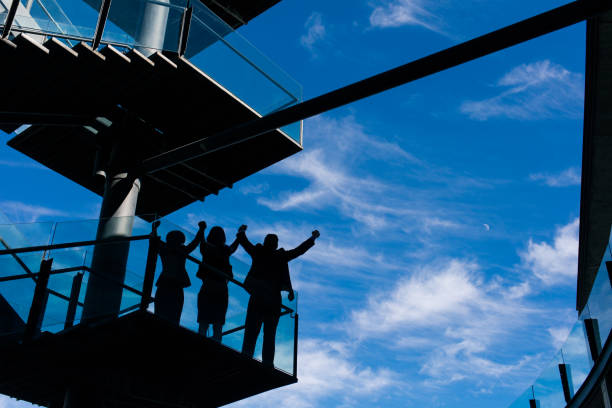 istock Young business people standing on balcony and raising arms 950478620