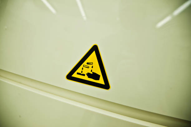 Yellow-Black Triangular Highly Corrosive Chemical Caution Sign On Storage Cabinet