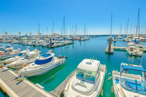Cascais, Portugal - August 6, 2017: yacht and motor boats docked at Cascais marina. The Marina is located under Cascais Cidadela. Summer holidays in sunny day. Turquoise bay. Blue sky with copy space.