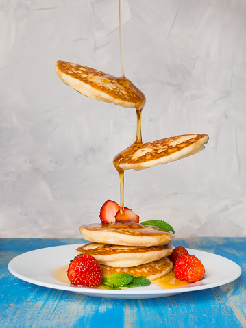 Flying pancakes with honey and strawberries. Vertical.