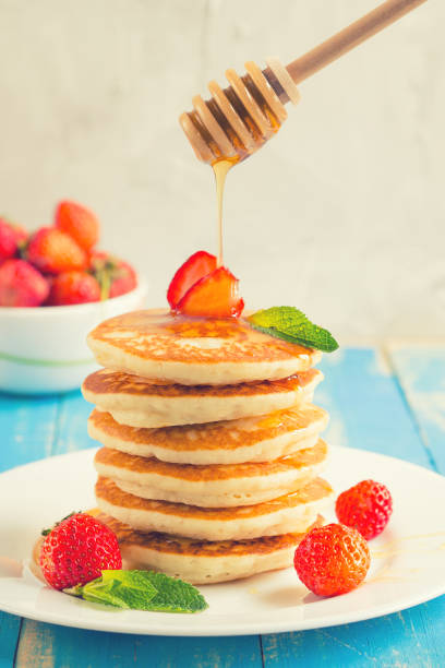 istock Stack of pancakes (fritters) with strawberries and honey on a plate. 950523506