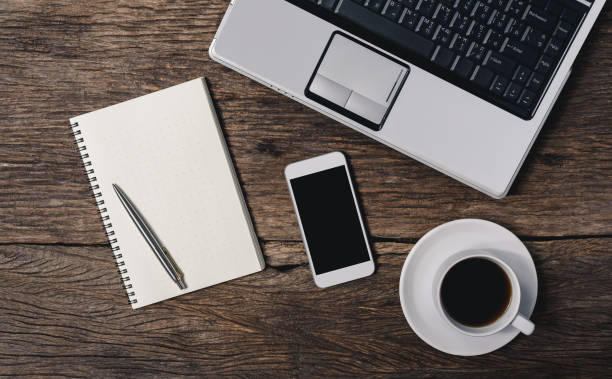 istock wooden table office stuff with notepad, laptop and coffee cup, notepad, pen, smartphone top view shot 950523718