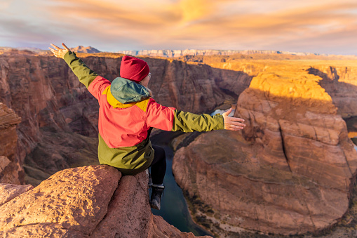 Stock photo of the gorgeous Horeshoe bend in Page Arizona at Sunrise with an active young hiker.