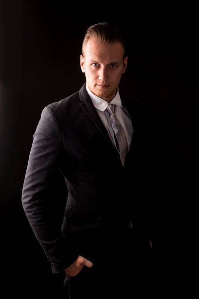 istock Handsome Businessman with black suit isolated on black background 950535572