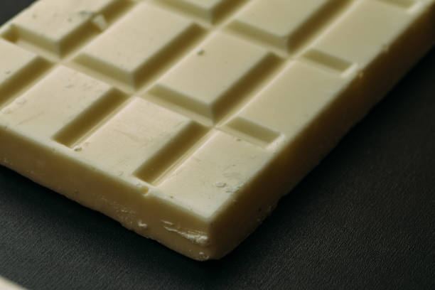 istock Tile or bar of white chocolate on black background, macro photo 950540920