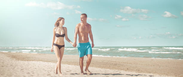 istock young couple walking on beach hand in hand 950550216